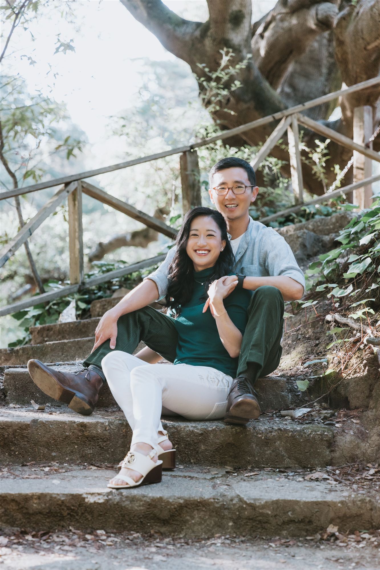 Helen and Richard sitting together on stone steps beneath an old sprawling tree